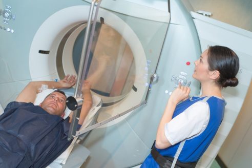 A patient going into an MRI or CT scanner, overseen by a healthcare worker