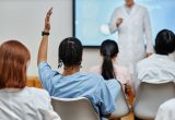 Back view at young black nurse raising hand in classroom